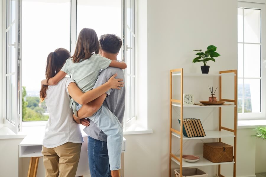 Glückliche Familie steht vor offenen Fenster