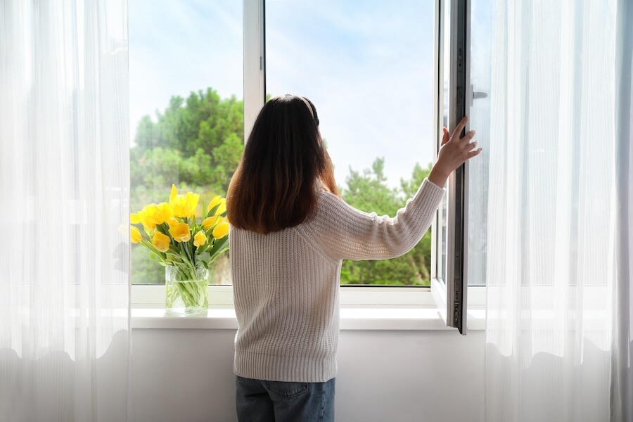 Junge Frau öffnet ein Fenster